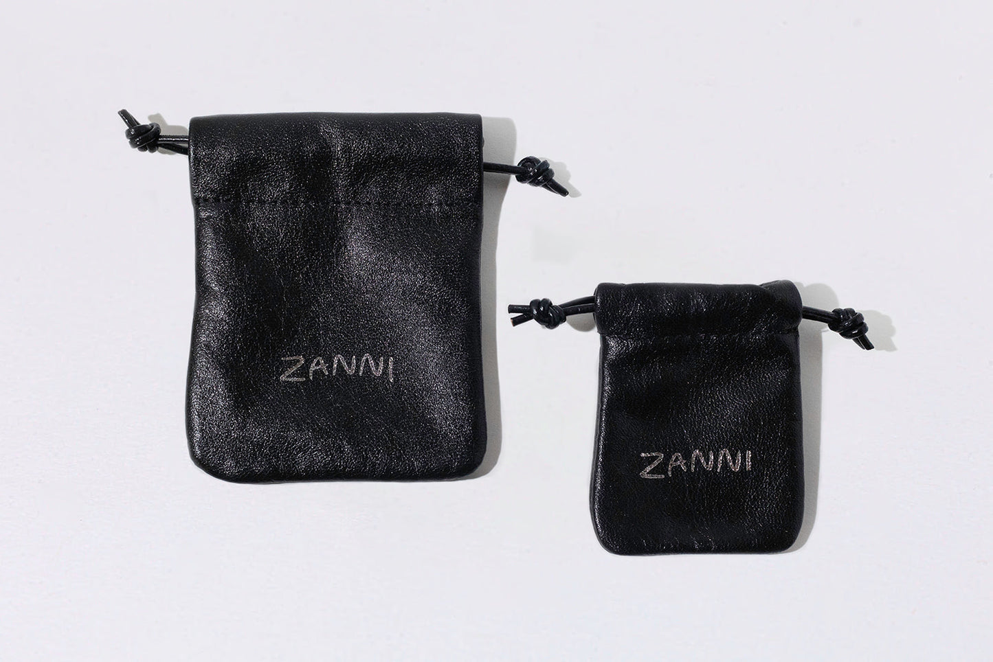 Two black velvet pouches with 'Zanni' branding on a white background