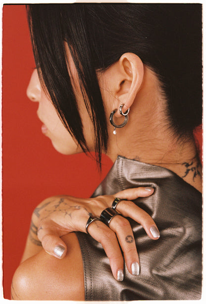 Close-up of a person with tattoos and jewelry against a red background