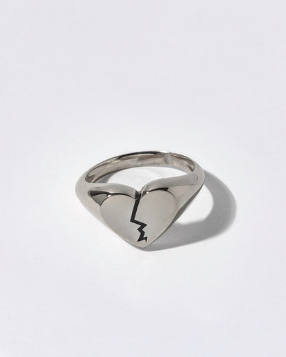 Silver ring with a broken heart signet on a white background