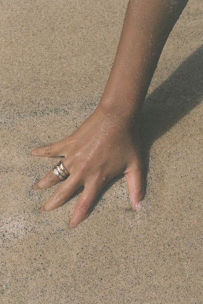 Hand with a ring on a sandy surface