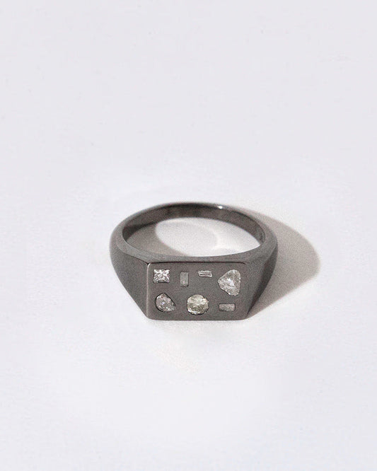 Black rhodium plated silver ring with embedded diamonds on a white background
