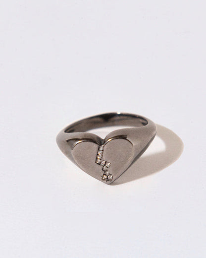 Black Rhodium Silver ring with a broekn heart design and white diamonds on a white background