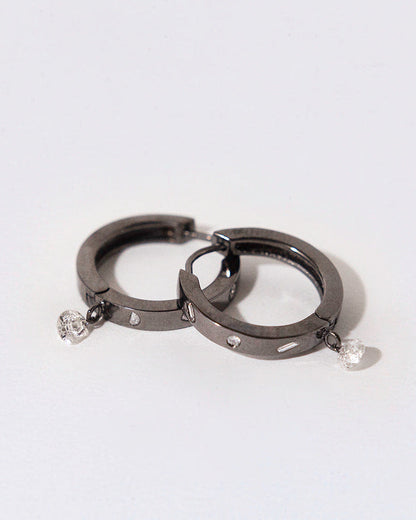 two black rhodium plated silver hoops with white diamond bezeled and a dangling diamond on a white background