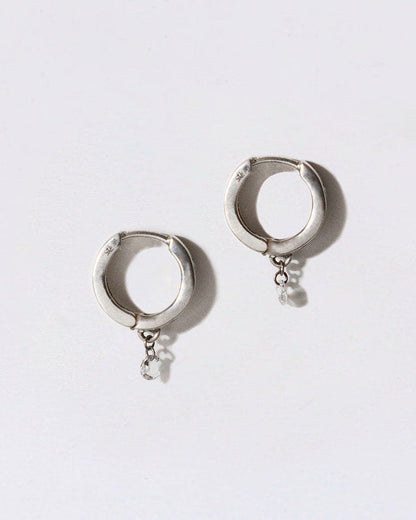 Silver hoop earrings with small dangling diamonds on a white background