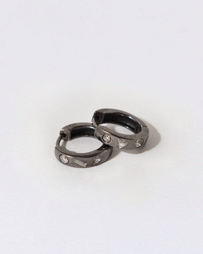 Two black rhodium plated silver metal earrings with embedded diamonds on a white background