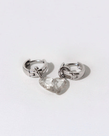 Pair of silver hoops with broken heart diamonds dangling as a charm on a white background