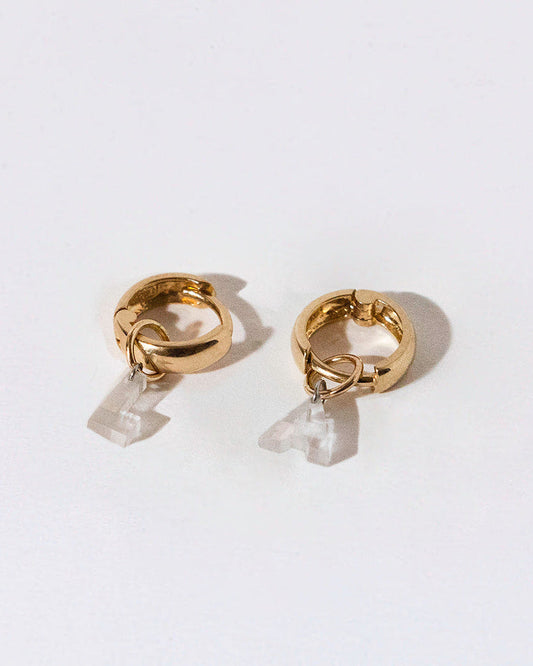 Pair of gold hoop earrings with small diamond letter charms on a white background