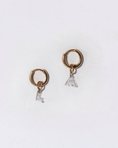 Pair of gold hoop earrings with small diamond letter charms on a white background