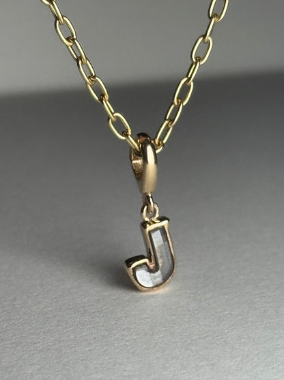 Gold necklace with a diamond letter 'J' pendant on a gray background