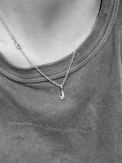 Silver necklace with a diamond letter 'J' on a gray shirt