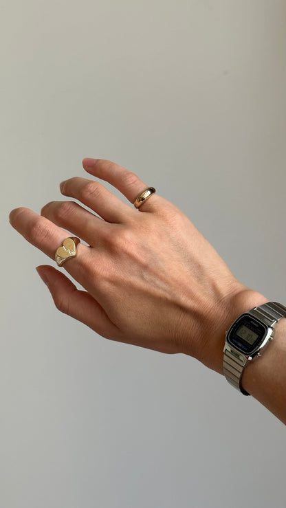 Person wearing two gold rings on their hand with a silver watch on