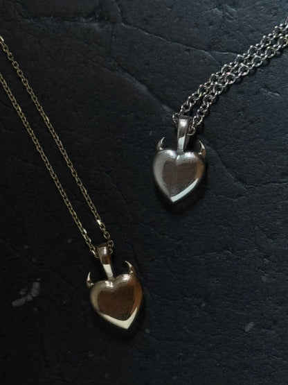 two heart shaped solid metal in silver and gold pendant with small horns