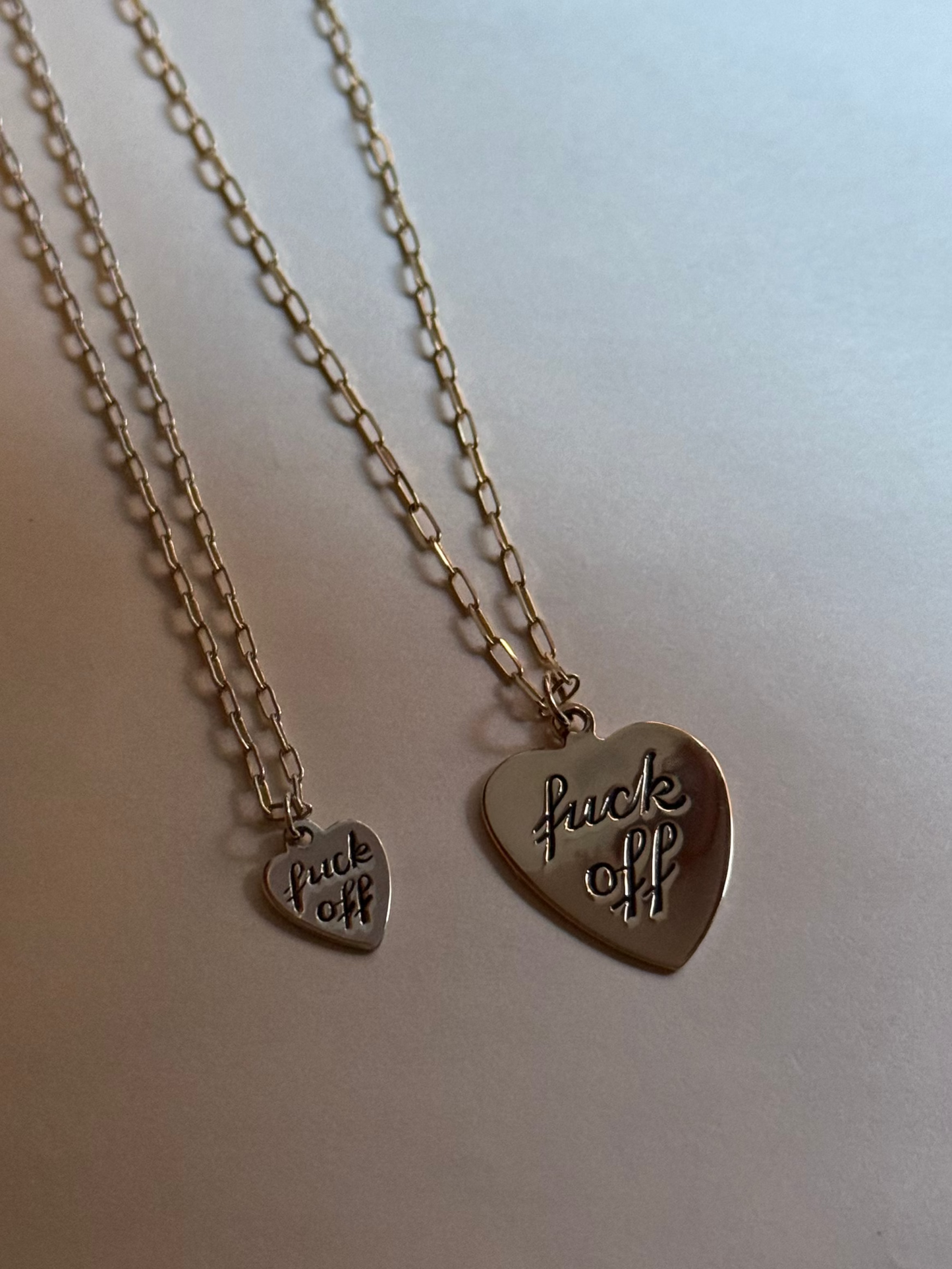 Two necklaces with heart-shaped pendants on a white surface