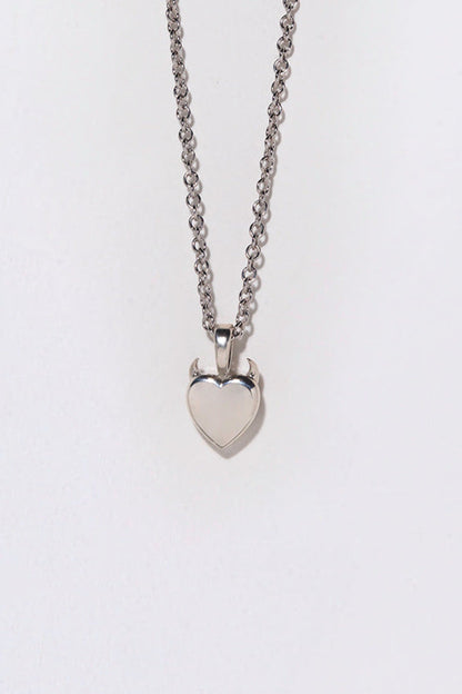 A silver necklace with a heart-shaped pendant topped with small horns.