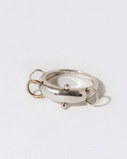 silver dome ring with four piercing that are silver and gold on a white background
