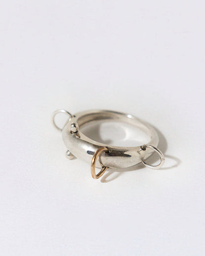 silver dome ring with four piercing that are silver and gold on a white background
