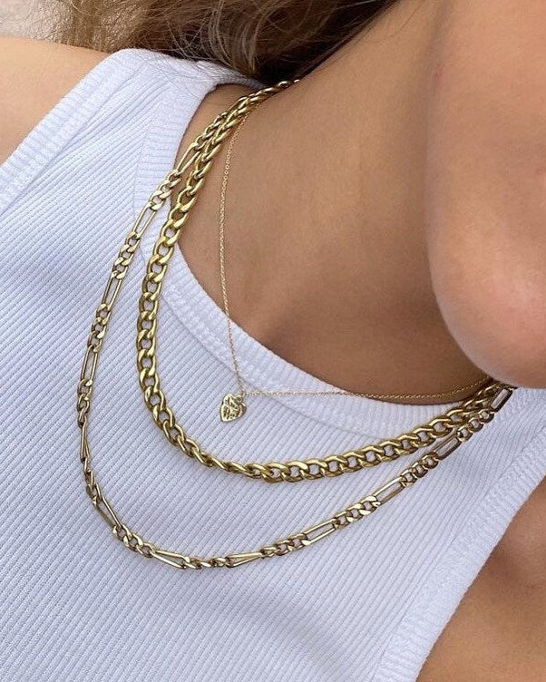 Close-up of a person wearing two gold necklaces on a white background