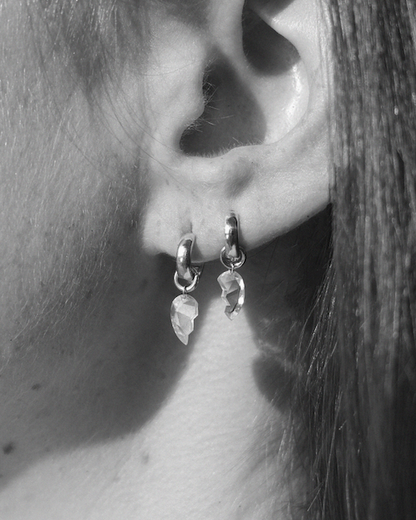 Pair of silver hoops with broken heart diamonds dangling as a charm on a person