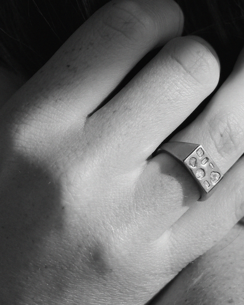 Close-up of a hand wearing a silver ring with embedded diamonds.