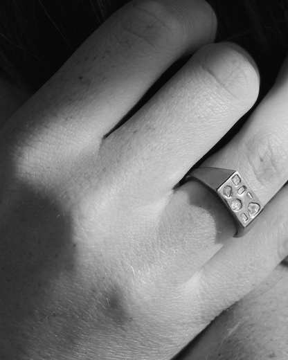 Close-up of a hand wearing a silver ring with embedded diamonds.