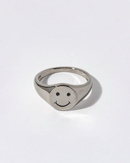 Silver ring with smiley face design on a white background