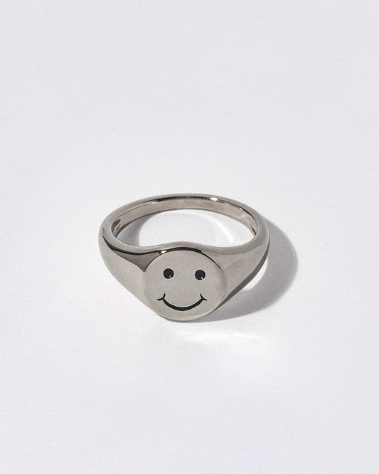 Silver ring with smiley face design on a white background