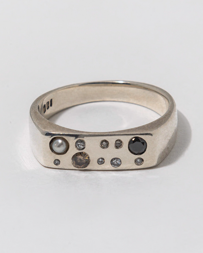 Silver ring with embedded diamonds on a light gray background