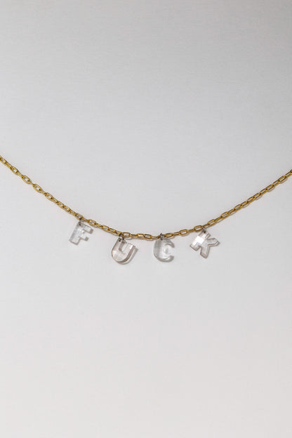 A necklace with the word 'FUCK' spelled out in white diamonds on a gold chain against a white background.