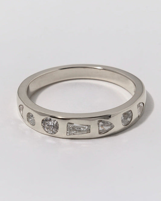 Silver ring with embedded diamonds on a light gray background