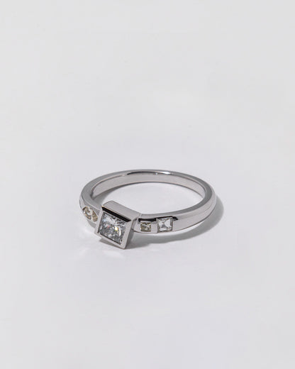 Silver ring with embedded diamonds on a light gray background
