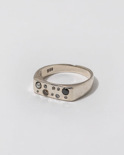 Silver ring with embedded diamonds on a light gray background