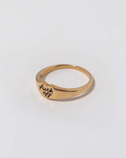 Gold ring with 'f**k off' engraving on a white background