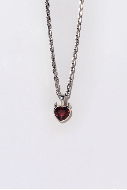 Necklace with a heart-shaped red ruby pendant with devil horns on a white background
