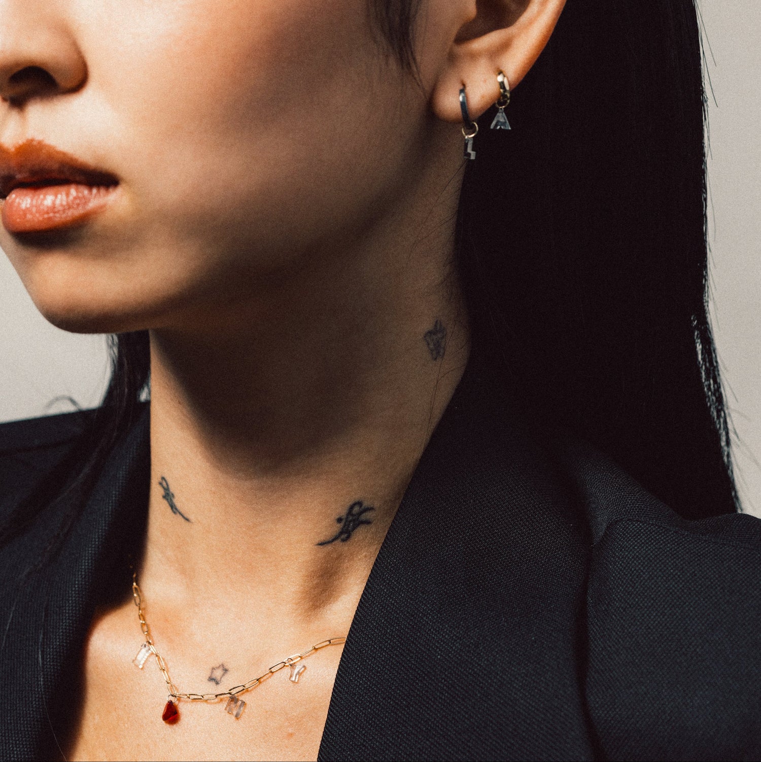 Close-up of a person wearing earrings and a necklace  that says " I Love N Y' with a neutral background